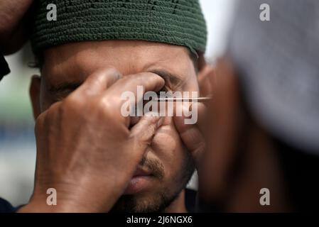 Guwahati, Assam, India. 03rd maggio 2022. Un uomo musulmano che applica Surma agli occhi prima di offrire la preghiera a un Eidgah per iniziare il festival Eid al-Fitr, che segna la fine del loro santo mese di digiuno del Ramadan, a Guwahati, Assam, India il 03 maggio 2022. Credit: David Talukdar/Alamy Live News Foto Stock