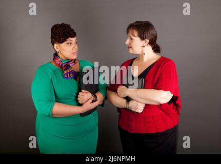 Due fiducioso Taglie donna d'affari fissando ogni altra con tensione nei loro volti Foto Stock