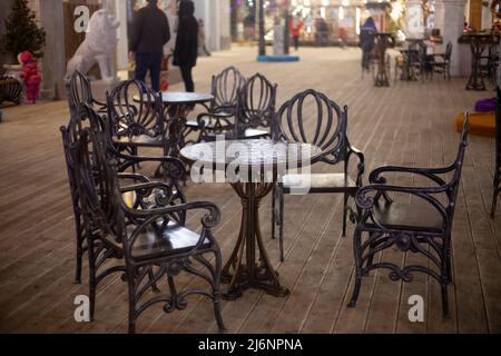 Tavolo monolitico in metallo. Mobili forgiati per un caffè all'aperto. Ristorante in città. Bel tavolo e sedie in metallo. Un pezzo di Foto Stock