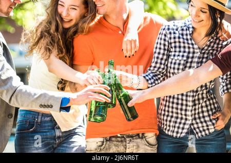 Amici felici gruppo bere e tostare birra in bottiglia in giorno di sole all'aperto - concetto di amicizia con i giovani millennial godere del tempo d'estate t Foto Stock