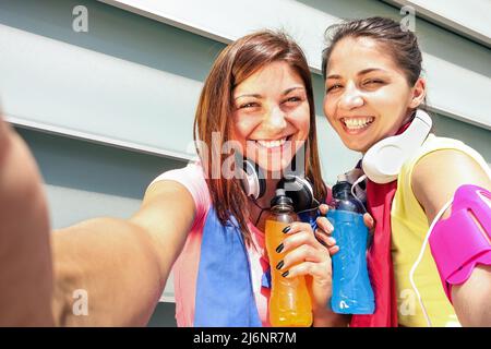 Fidanzate sportive che prendono selfie durante una pausa alla corsa di allenamento in zona urbana - Sport giovani donne felici che si divertono insieme al fitness jogging worko Foto Stock