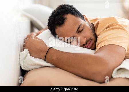 Middle Eastern Man addormentata sullo stomaco abbracciando il cuscino al chiuso Foto Stock
