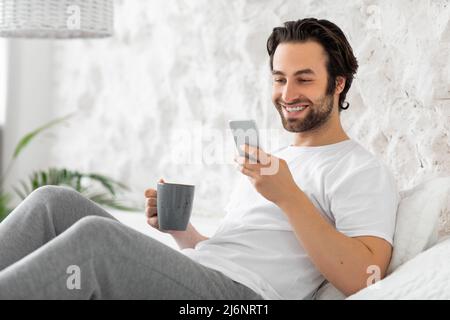 Ragazzo rilassato barbuto che si agghiacciano a letto a casa Foto Stock