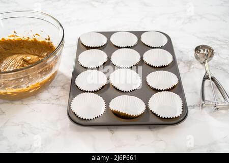 Foderare la teglia per cupcake con i rivestimenti per cupcake in lamina per cuocere i cupcake di pan di zenzero. Foto Stock