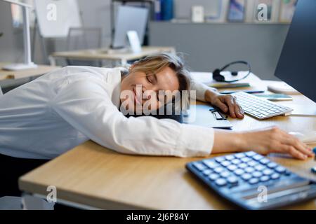 Lavoratore di ufficio femminile con occhi chiusi che si appetta sul posto di lavoro Foto Stock