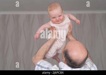 Nonno in possesso di una ragazza caucasica 8 mesi che gioca in camera da letto Foto Stock