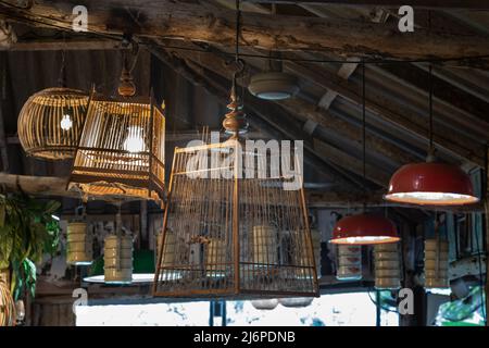 Vecchia gabbia di uccelli in legno appesa a un soffitto con travi in legno per decorare l'interno di un pub o ristorante in stile country. Gabbietta d'uccello d'epoca, uccello d'epoca Foto Stock