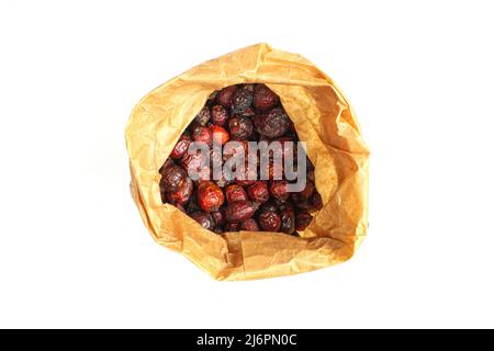 Sacchetto di carta pieno di fianchi di rosa secchi dall'alto e isolato su sfondo bianco Foto Stock