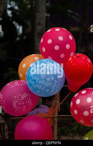 Collezione di palloncini colorati con disegni diversi e 'Happy Birthday' scritto. Messa a fuoco selettiva con sfocatura dello sfondo. Foto Stock