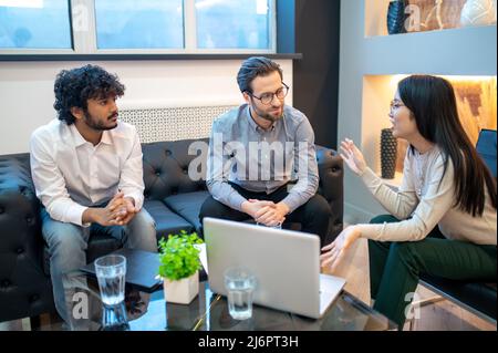 Dipendente di ufficio femminile che parla con i suoi colleghi Foto Stock