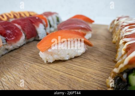 Vista ad angolo e selettiva di una varietà di sushi roll su un tagliere di bambù Foto Stock