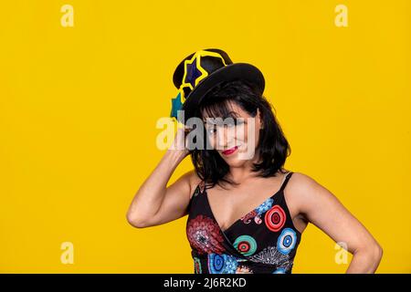 Bella donna indossa occhiali gialli a forma di stella e un cappello. La giovane donna bruna è felice e divertirsi alla festa. Foto Stock