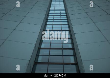 Alto edificio nei giorni grigi. Dettagli dell'architettura. Superficie della parete. Vetri in casa. Foto Stock