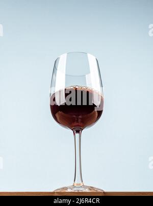 Vista dal basso di un bicchiere con vino rosso su una superficie di legno. Spazio di copia. Foto Stock