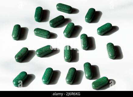 Pillole di clorella, spirulina, erba d'orzo su sfondo bianco con ombre scure primo piano supplemento nutrizionale, detox superfood vista dall'alto Foto Stock