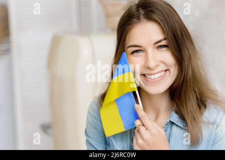 Libera sorridente ragazza che tiene bandiera Ucraina nelle sue mani, chiedendo la pace. Patriot del suo paese. Prega per l'Ucraina. Lotta per la libertà. Fermare la guerra Foto Stock