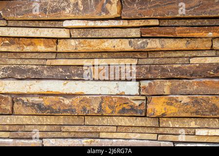 Muro di pietra impilato a secco fatto di grandi lastre di sfondo colorato arenaria Foto Stock