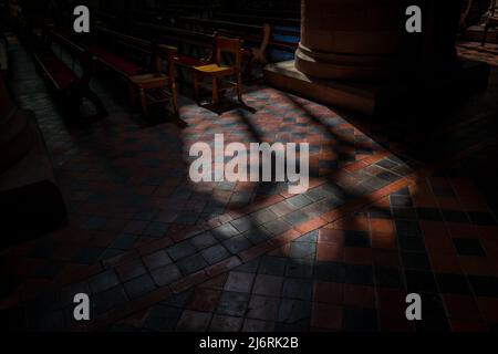 Luce e ombra su un pavimento di piastrelle rosse e nere da una finestra di vetro colorato nella Cattedrale di Hereford, Herefordshire, Inghilterra, Regno Unito Foto Stock