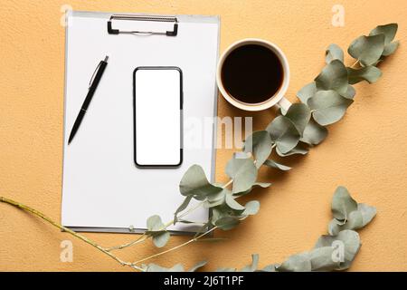 Composizione con telefono cellulare, tazza di caffè e ramo di eucalipto su sfondo colorato Foto Stock