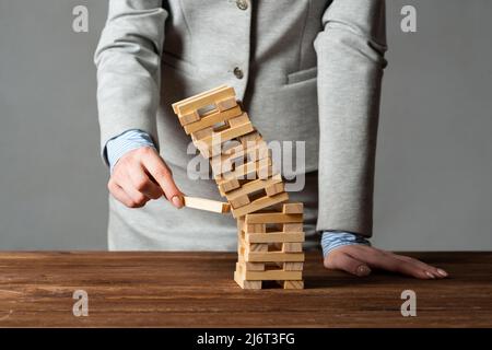 Uomo d'affari che rimuove il blocco di legno dalla torre Foto Stock