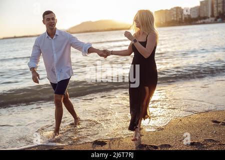 Coppia spensierata che si gode la serata sulla spiaggia insieme Foto Stock