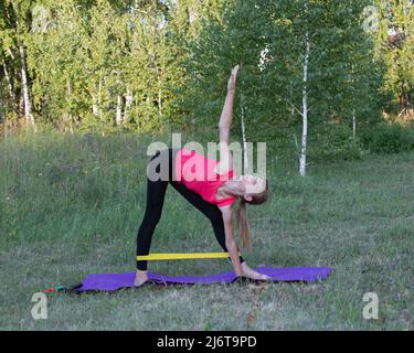 Teen girl pratica yoga in Utthita Trikonasana, esteso triangolo posa. Foto Stock