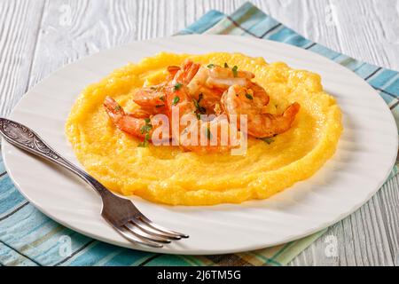 Primo piano di Polenta e schie fritte, piatto veneziano, polenta con gamberetti fritti su piatto bianco su tavola in legno testurizzato, vista orizzontale dall'alto Foto Stock