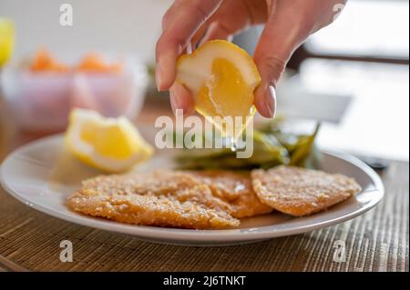 Spremere il limone su una cotoletta di ceci vegana Foto Stock