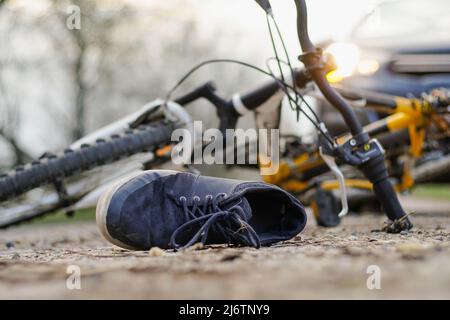 Primo piano di una sneakers sulla strada vicino alla bicicletta dopo un incidente d'auto. Foto Stock