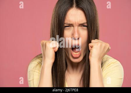 MAD emotiva arrabbiata donna che si sostiene su di voi su sfondo rosa studio Foto Stock