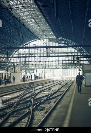 Uomo che cammina nel terminal lungo la ferrovia Foto Stock