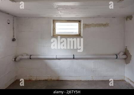 Il nuovo tubo fognario passa attraverso un locale vuoto nel seminterrato di una casa Foto Stock