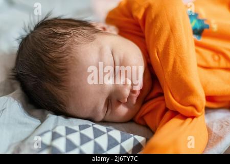 Il neonato di colore arancione chiude i dorsi nel letto Foto Stock