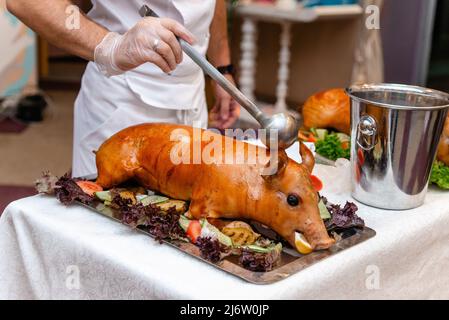 Maiale intero arrosto decorato con verdure brillanti come peperone e cetrioli. Foto Stock