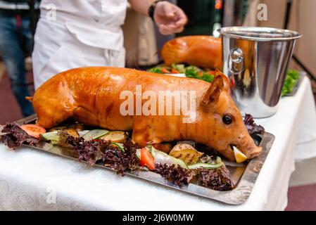 Maiale arrosto. Maialino arrosto con verdure sul piatto. Foto Stock