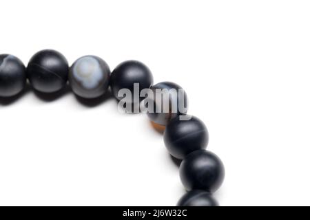 Bracciale di agate nere tonde isolate su sfondo bianco, primo piano frammento di foto con messa a fuoco selettiva Foto Stock