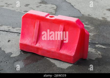 La barriera stradale in plastica rossa si trova su strade urbane bagnate Foto Stock
