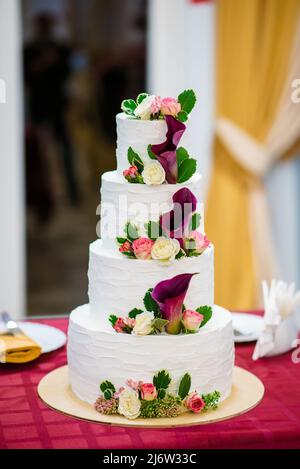 Bella casa matrimonio quattro-tiered torta decorata con fiori rosso primavera e modello fatto a mano. Il concetto di dessert deliziosi Foto Stock