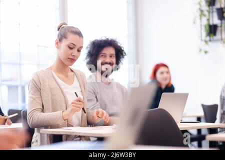 Studenti multietnici che ascoltano un docente in un'aula. Giovani intelligenti studiano in un college. Foto Stock