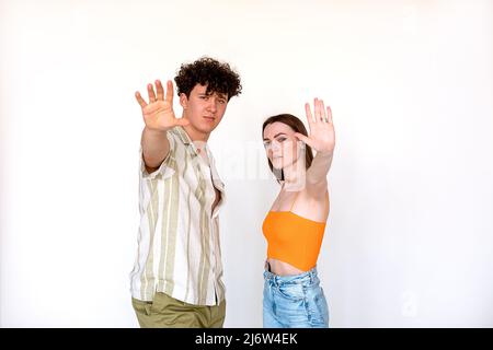 Ritratto di giovane coppia fiduciosa bella in posa su sfondo bianco. Giovane uomo, donna con palma aperta, cinque segni. Foto Stock
