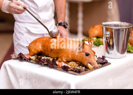 Maiale arrosto. Maialino arrosto con verdure sul piatto. Foto Stock