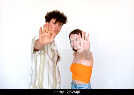 Ritratto di giovane coppia preoccupata bella posa su sfondo bianco. Giovane uomo e donna con palma aperta, cinque segni. Foto Stock