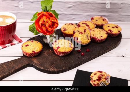 Diversi muffin al ribes serviti su un piano rustico con una tazza di cappuccino Foto Stock