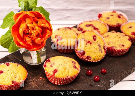 diversi muffin al ribes serviti su un vecchio asse di legno con bouquet di fiori Foto Stock