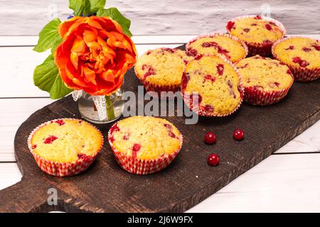 diversi muffin al ribes serviti su un vecchio asse di legno con bouquet di fiori Foto Stock