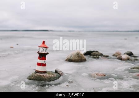 Mare d'inverno ghiacciato con faro decorativo. Stile di vita nautico. Inverno, Mare, Viaggi, avventura, vacanze e vacanza concetto. Viaggia nel 2021 Foto Stock