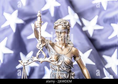 La statua di giustizia Themis o Iustitia, la dea della giustizia bendata contro una bandiera degli Stati Uniti d'America, come un concetto legale. Foto Stock