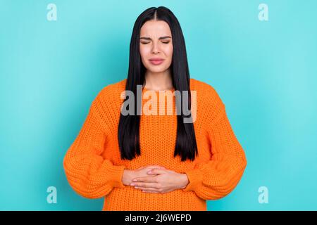 Foto di infelice signora turbata vestita braccia di pullover in maglia stomaco con dolore isolato colore teale sfondo Foto Stock