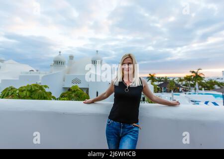 Giovane ragazza in piedi sul balcone che si affaccia sul mare Foto Stock