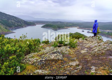 Uomo che contempla il paesaggio impersonante della valle con un lago blu. Foto Stock